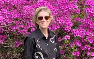 Ann Friedman in front of bright purple flowers