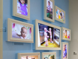 Babies on framed monitors mounted on a light blue wall